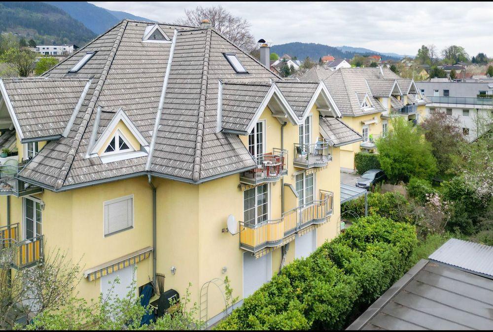 Willkommen in unserem modern und elegant gestalteten Wohnanlage, die von uns als Bauträger errichtet und verkauft wurden. Dieses Bild zeigt das schöne Äußere der modernen Gebäude, umgeben von Grün und Bäumen. Im Hintergrund können wir den klaren blauen Himmel und eine ferne Stadtlandschaft sehen. Diese Wohnanlage bietet luxuriöse Wohnräume, hochmoderne Annehmlichkeiten und eine friedliche Umgebung, die die Bewohner ihr Zuhause nennen können.